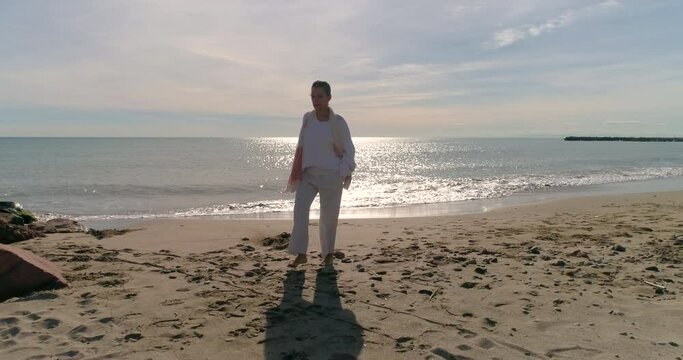 Madura paseando relajadamente por la orilla de la playa y dron volando delante