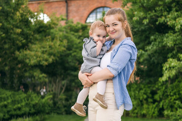 Fototapeta premium A young mother walks with a one-year-old baby. What to do while walking with your child