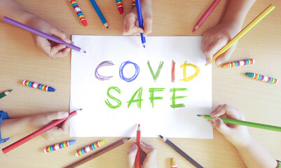 covid safe concept. Children write COVID SAFE on white paper
