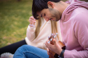 man playing a song to his girlfriend at picnic