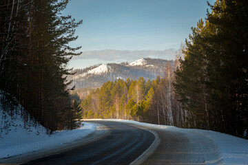 mountainous terrain, mountain pass, wilderness and winding road. beautiful view of the mountains from the road in the forest. sunlight falls on mountains and trees. mountains on the horizon.