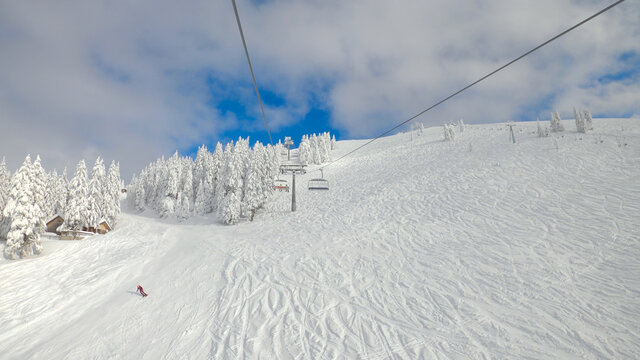 POV: Riding the ski lift over the tracked slopes of a ski resort in Slovenia.