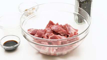 Chopped raw pork meat in a glass bowl on white background