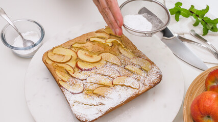 Fresh baked Apple pie on a serving board. Topping cake with powdered sugar.