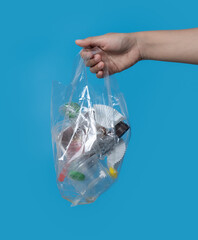 Hand holding clear plastic bag of garbage isolated on white background