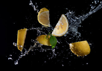Slices of lemon with splash water isolated on black background.