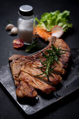 Pieces of of grilled pork with herbs on dark table