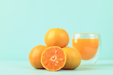 Fresh tangerine orange fruit and juice in glass on color background