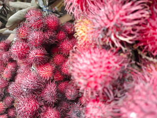 Fresh delicious sweet red rambutan, seasonal asian hairy fruit, sell in a traditional market in...