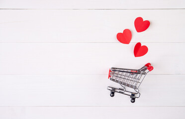 Shopping cart and heart shape paper on wooden table, sale concept in festive valentine day February...