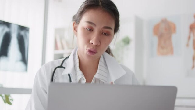 Asian female doctor using laptop computer online video call remote talking to patient, prescribe medicine. Tele medical, telehealth, hospital clinic health care service, or internet technology concept