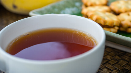 Tea time in warm afternoon, round white tea cup and flowers and snakes on table.