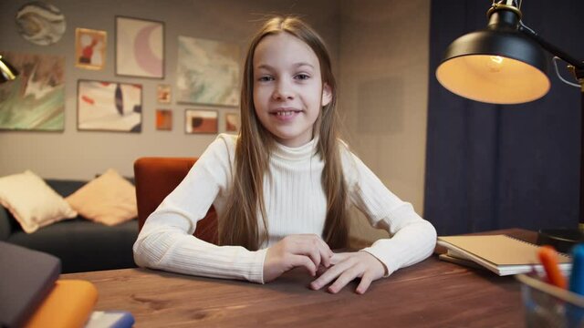 Girl kid making video call with laptop at home, using camera zoom online virtual class, social distancing, learning remotely at school during covid coronavirus lockdown