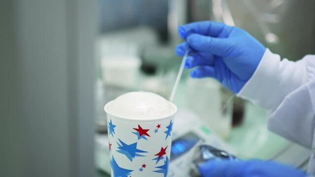 Scientist with Blue Gloves doing Experiments with Rising Styrofoam in Chemical Laboratory of Polyurethane Factory in slowmo