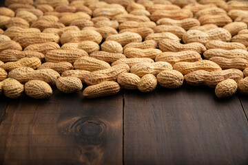 Unpeeled peanuts on wooden table background with copy space. (arachis hypogaea) Edible seeds....