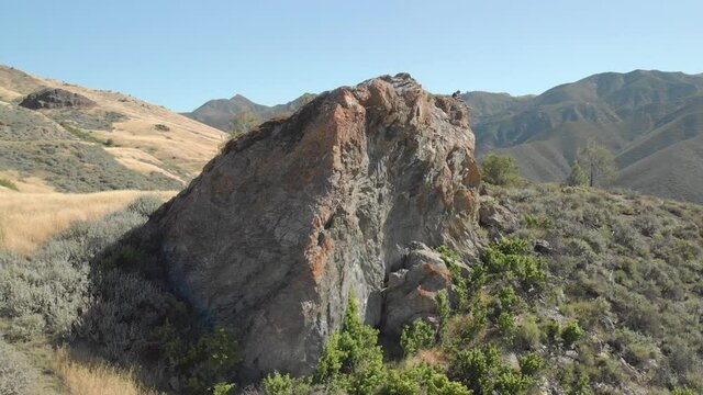 Photographer, Hiker Sitting Atop Impressively Large Climbing Boulder Near Santa Barbara, California. Wide Drone Shot Circling Right, Reveal.