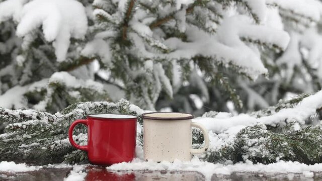 two cups of coffee on wooden table in snow