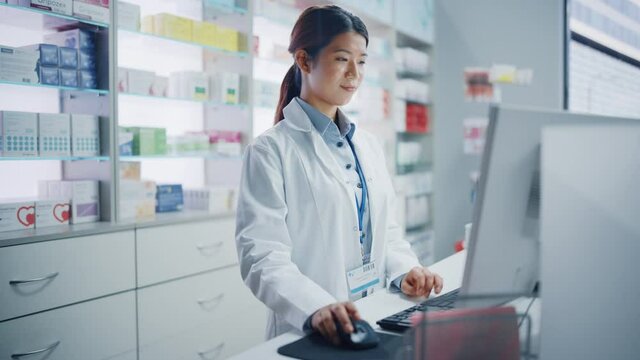 Pharmacy Drugstore: Beautiful Asian Pharmacist Uses Checkout Counter Computer, Does Inventory Checkup, Online Prescription of Medicine Packages, Drugs, Vitamin Boxes, Supplements, Health Care Products