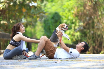 Asian couple is playing with their beagle dog while having morning exercise in the park