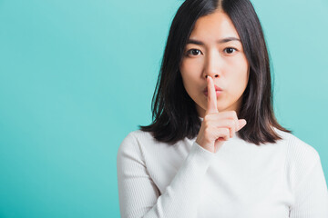 woman holding index finger on her mouth lips