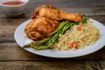 Roasted chicken drumsticks with rice on rustic wooden background,