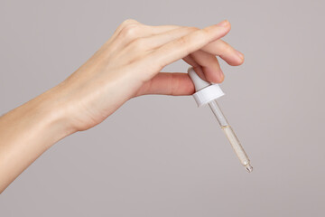 Hands of a woman holding an eyerdropper with fluid