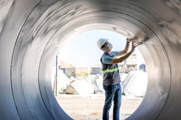 The inspector is inspection to the large steel spiral pipe in the construction site.