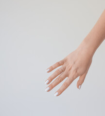  Female hand with a beautiful manicure on a background of a white wall. Delicate and healthy skin on the hands, rejuvenation of the skin of the hands, moisturizing and care