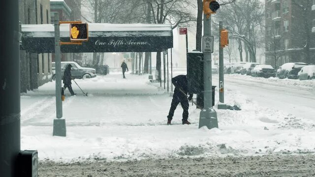 man plowing snow, men shoveling on snowy day - winter blizzard in New York City