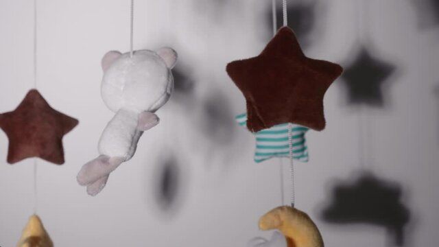 Woven Toys Hanging On Crib Mobile With Lullaby Music Inside A Nursery Room. - close up
