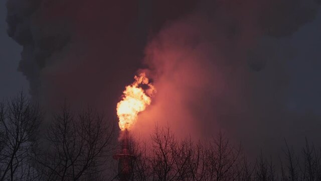 Burning dangerous gases at the flare stack of an oil refinery during the night