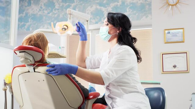 A dentist is mask checks patient's teeth while the patient looks in the mirror