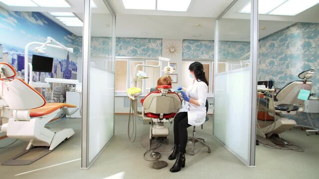 Dental cabinet devided into three sections. In the middle a dentist is working with a patient. 