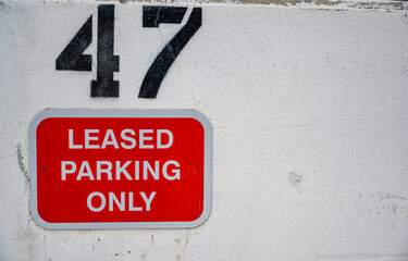 Leased Parking sign with assigned number on a white wall