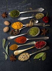 Various spices spoons on black table. Top view with copy space