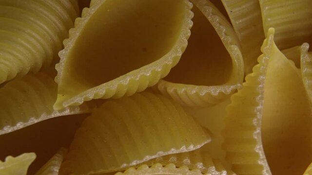 Pasta for food, rotation. Macaroni - Mini Conchiglie Rigate close up.