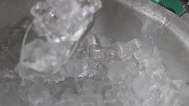 scooping ice cubes for drinks from an ice bucket via metal scoop in slow motion