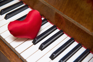Red hearts lie on the piano keyboard.
