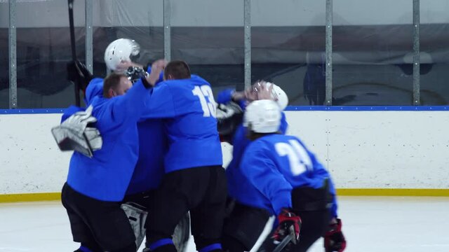 Joyous Hockey Players Throwing Away Helmets, Skating To Each Other On Ice Rink And Jumping In Huddle While Celebrating Goal