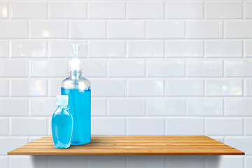 Alcohol sanitizer hand gel cleaners big size and small size for anti virus on wood shelf at white ceramic tile wall pattern background.
