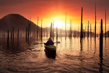 Adventurous Girl kayaking on an infatable kayak in a beautiful lake. Colorful peaceful Sunrise Art Render. Taken in Stave Lake, East of Vancouver, British Columbia, Canada. Adventure, vacation concept