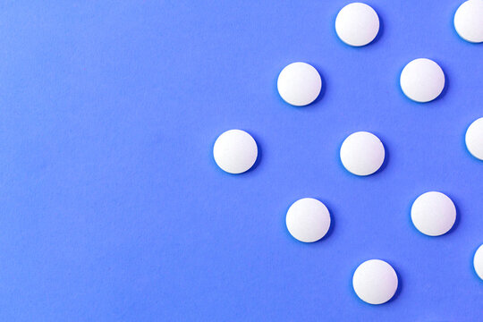 Image of a row of pills, drugs, and tablets. Place them on a colorful blue surface.
