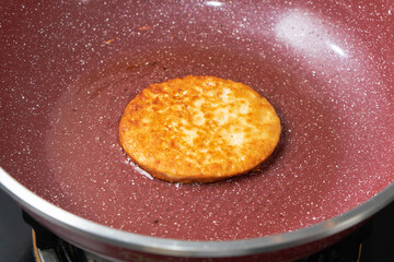 minced meat or burger meat being fried in red frying pan. close-up