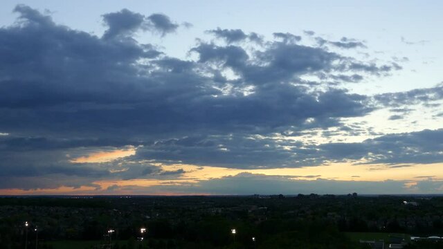 Amazing time-lapse of clouds above dark suburb at sunset.