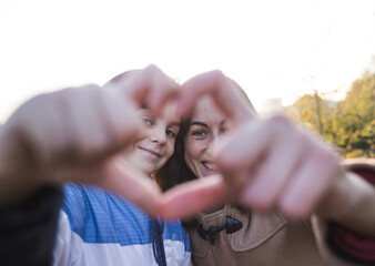 Boy with mom folded fingers in the shape of a heart.