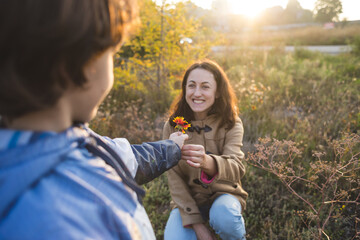 A child gives a flower to his mother