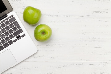 Office desk with laptop and apple fruits
