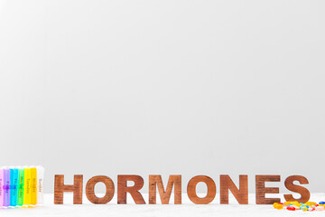 Word HORMONES and pills on light background
