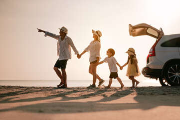 Asian family on the beach.Vacation time. Happy father, mother and son enjoying road trip the summer holidays.Parents and children are sitting on a hatchback with a sea background. - obrazy, fototapety, plakaty