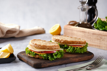 Sandwich with cheese, tomato and fresh salad, made of whole wheat bread with a crispy crust on a wooden board close-up